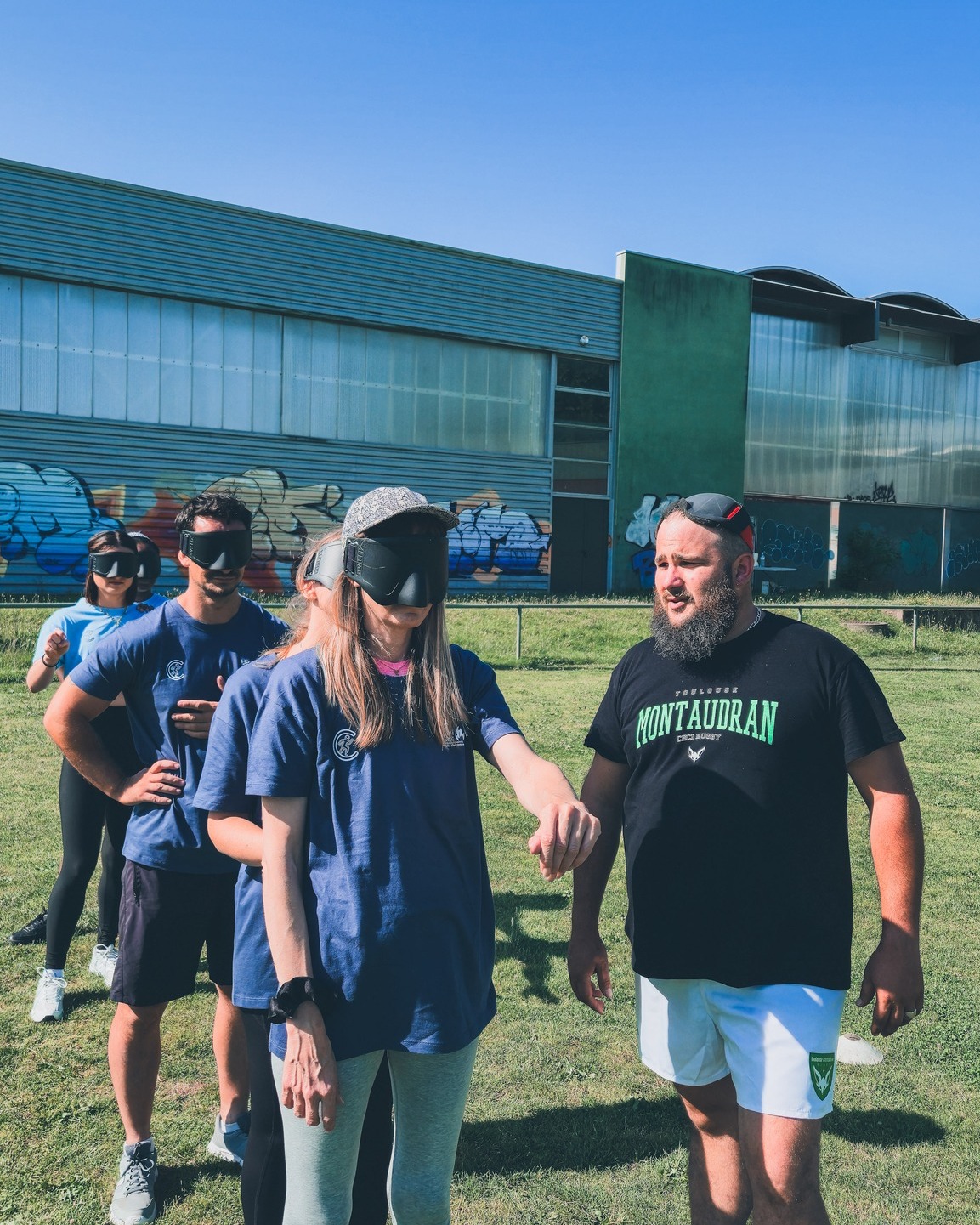 Des personnes à la queue portent un masque sur les yeux, prises de face.