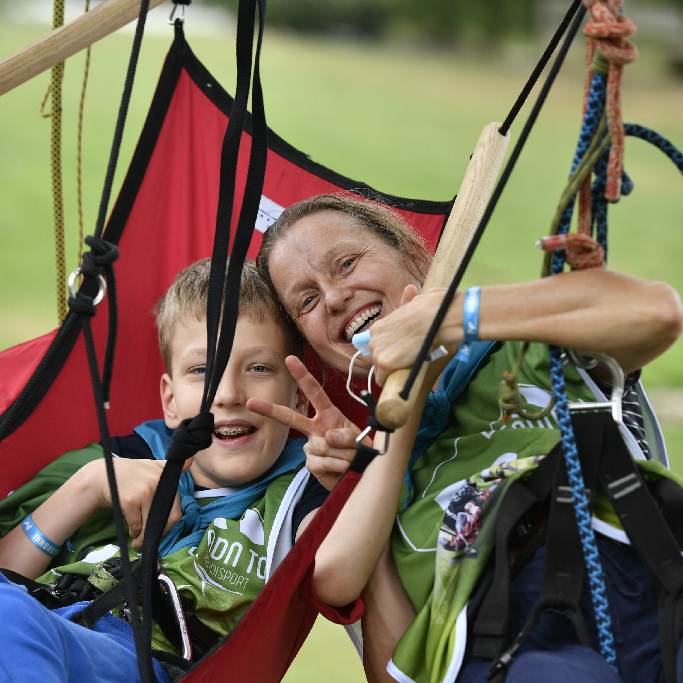 Une femme et un enfant pratiquant de l'acrobranche adapté pris en photo de face.