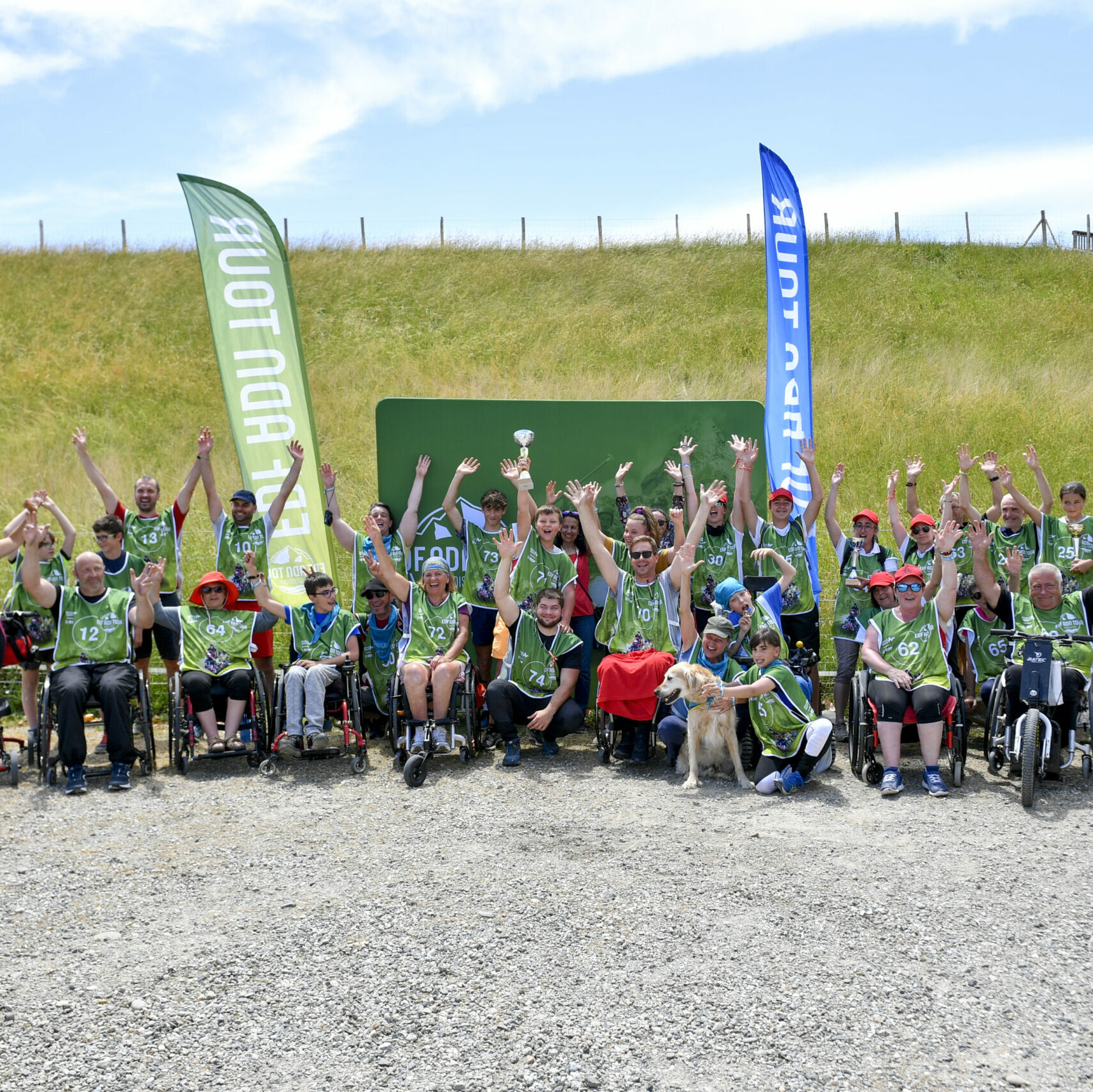De nombreuses personnes rassemblées avec des chasubles verts, elles lèvent les mains en l'air, pris de face. 