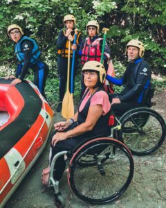 Cinq personnes s'apprêtant à monter à bord d'un raft, certaines ont des pagaies dans leur main, pris sur le côté.