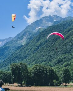 Deux parapentes dans les airs avec un fond montagneux.