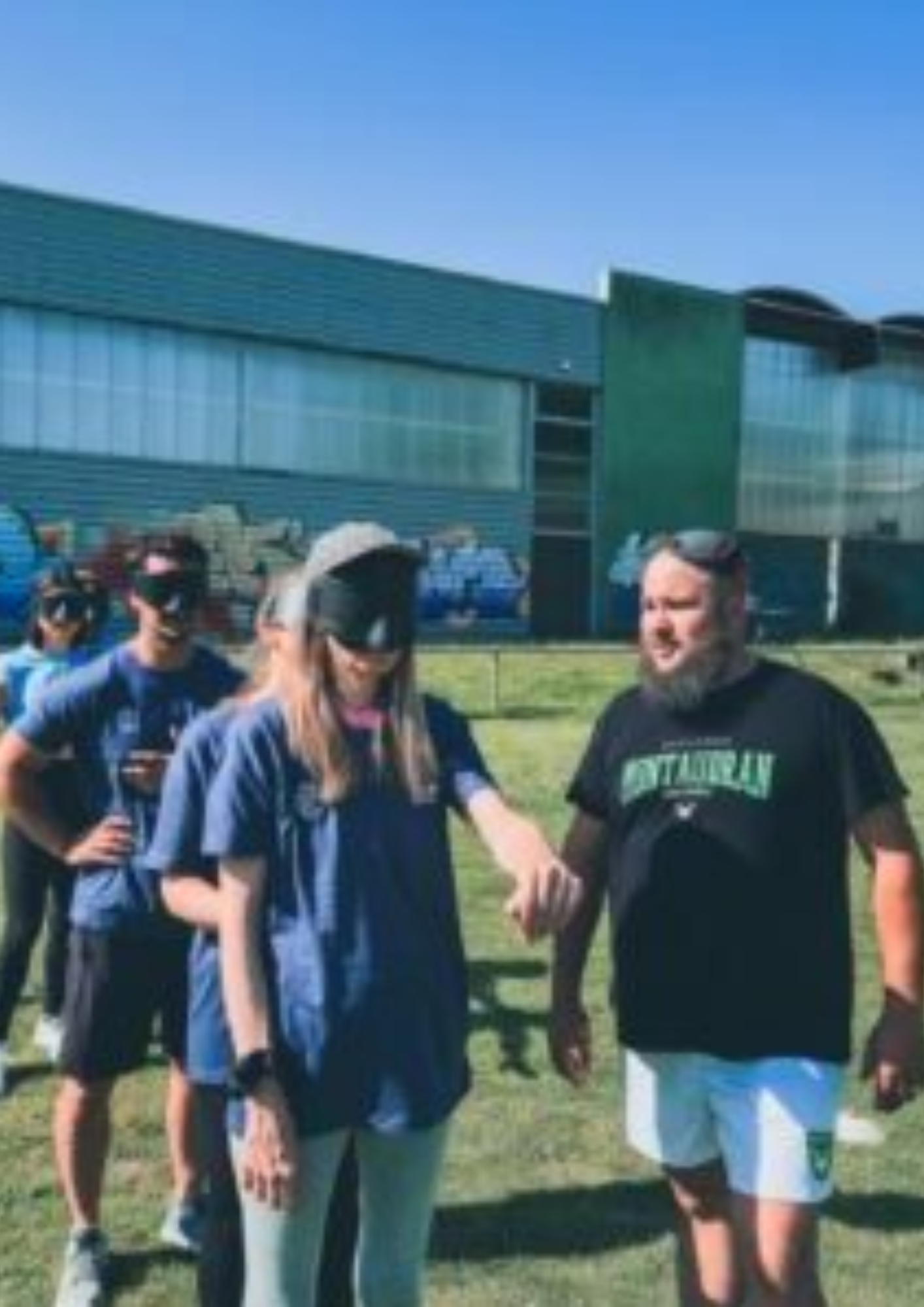 Des personnes à la queue portent un masque sur les yeux, prises de face.