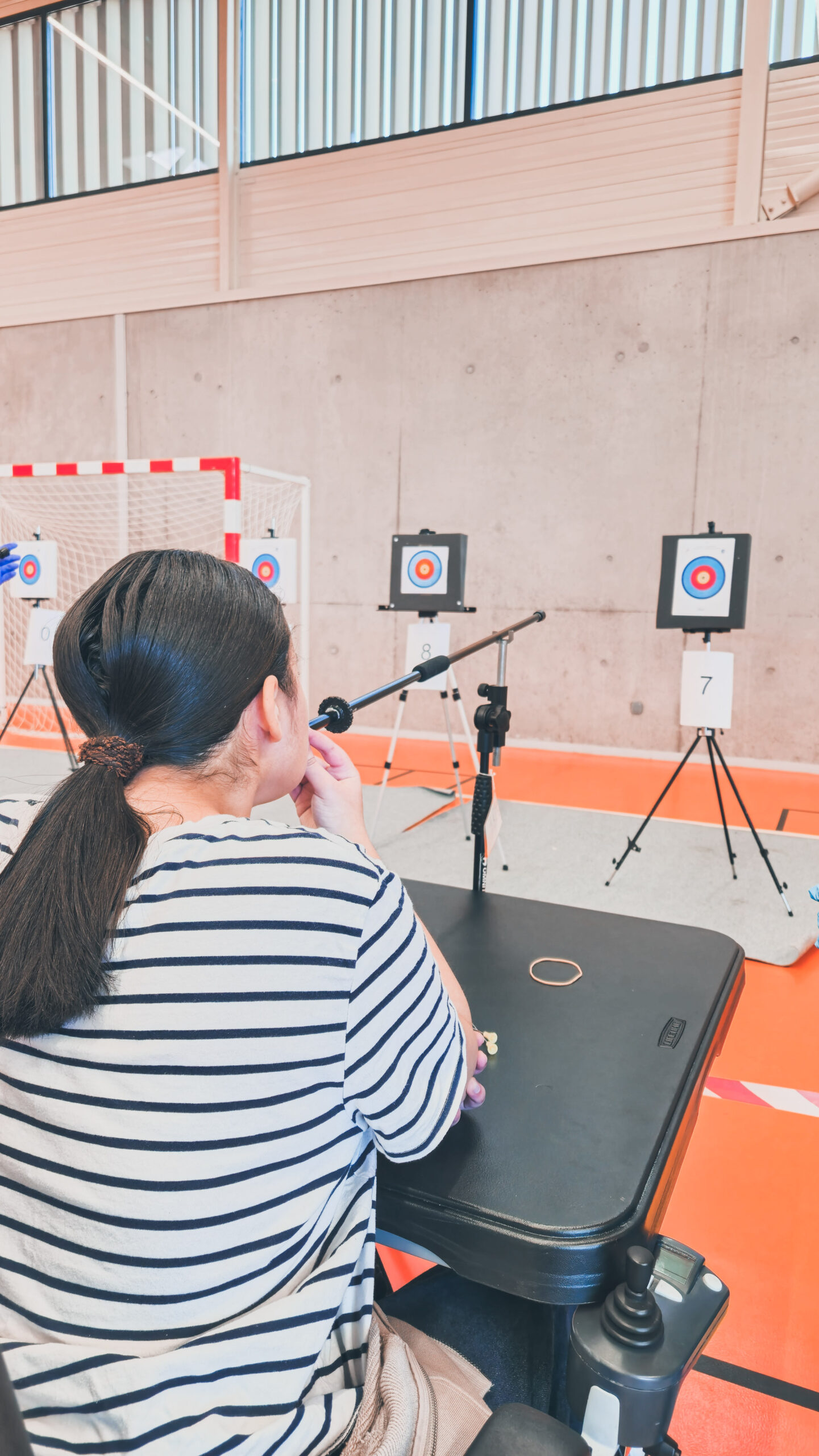 Une personne s'apprêtant à tirer sur la cible avec une sarbacane avec potence, prise de dos.