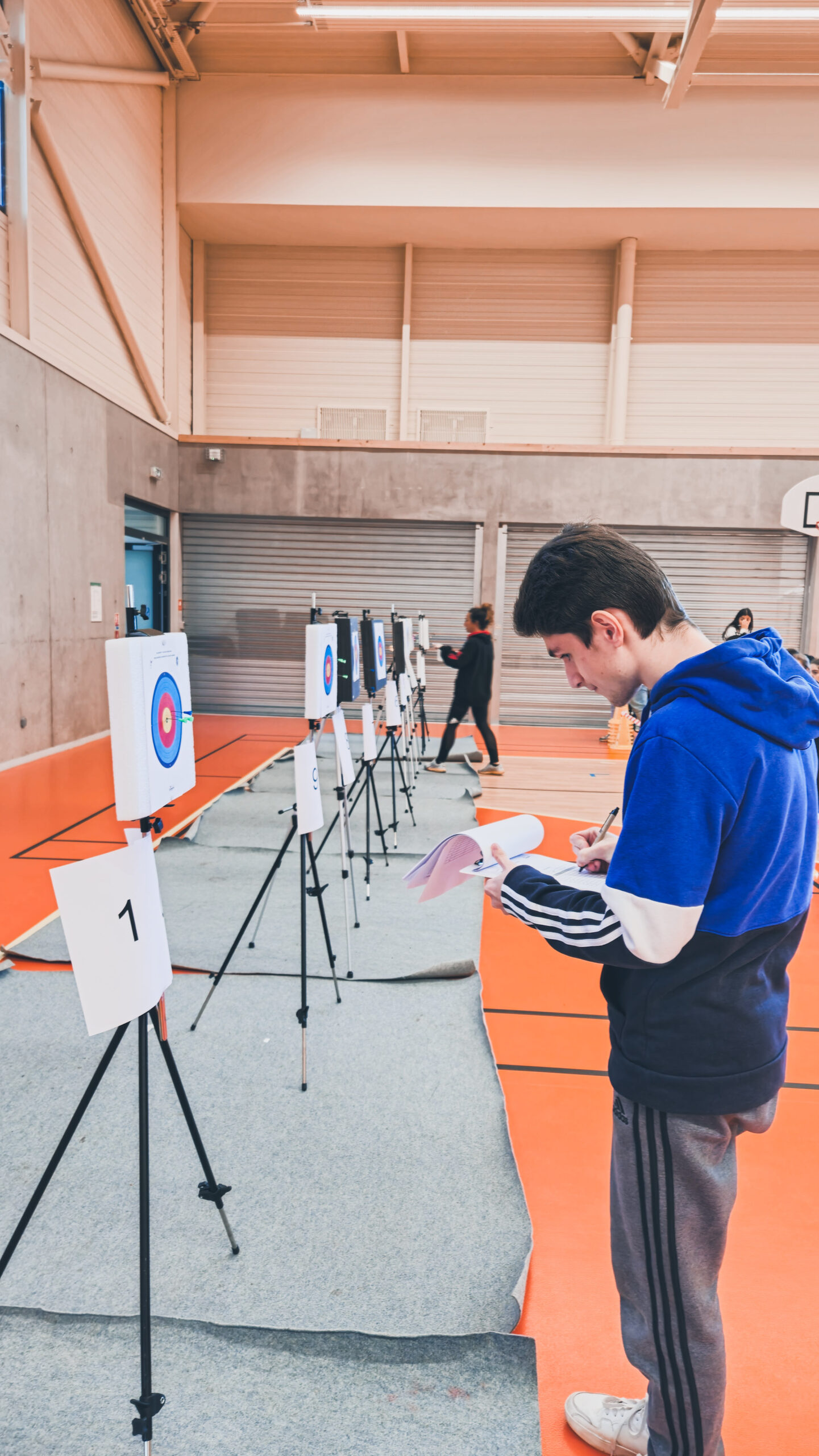 Un arbitre entrain de prendre les scores sur les cibles, pris sur le côté
