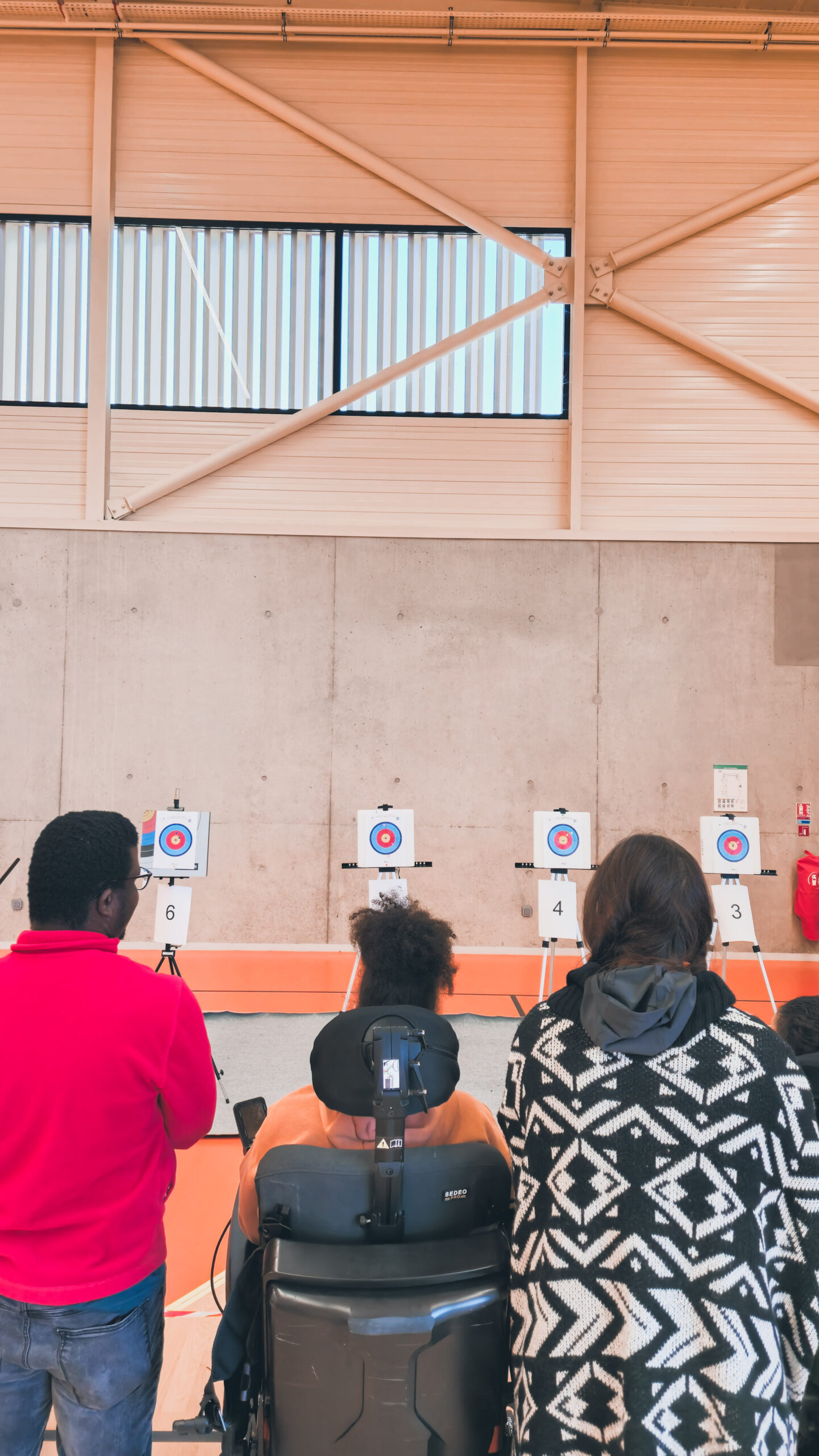 Trois personnes face aux cibles, prises de dos.